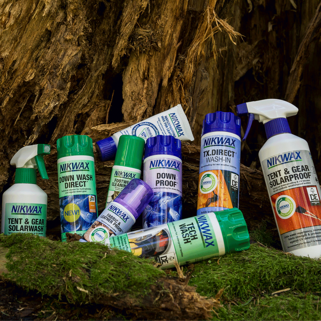 Variety of Nikwax waterproofing products for outdoor gear, including Tent Wash and Down Proof, displayed on moss.