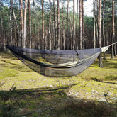 Bushmen Jungle Hammock with mosquito net hanging in a forest, perfect for outdoor camping and protection from insects.