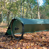DD Tarp S set up as a ground bivi shelter among autumn leaves in a forest, ideal for wet weather camping.