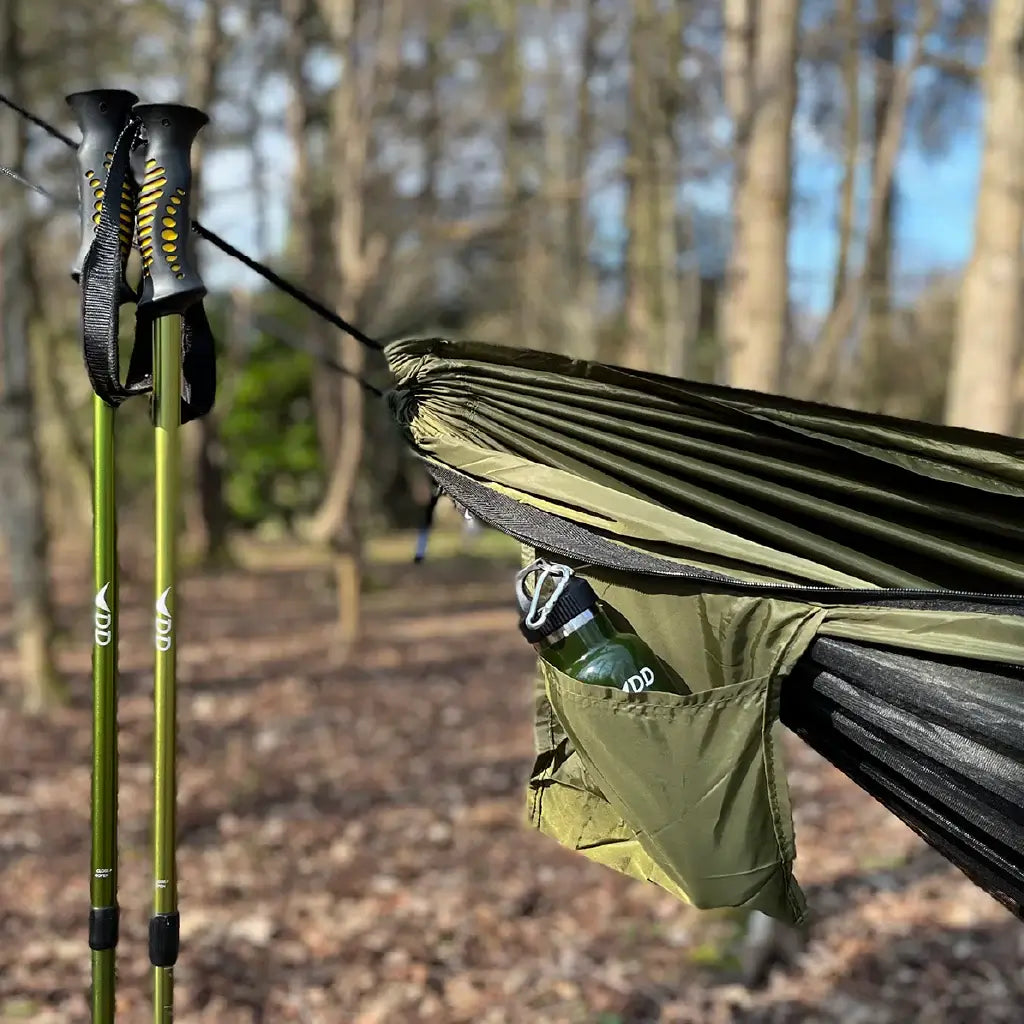 DD Recycled Frontline Hammock with water bottle and trekking poles in a natural outdoor setting. DD Recycled Frontline Hammock with water bottle and trekking poles in a natural outdoor setting.