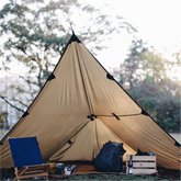 DD Hammocks 3x3 tarp set up in a bushcraft campsite, showcasing its A-frame structure and gear inside.