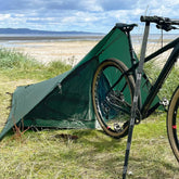 DD SuperLight Bikepacker Mesh Tent set up next to a bicycle on a grassy shore, perfect for bug-free camping.