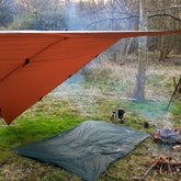 DD Hammocks Magic Carpet set up as a shelter over a picnic blanket and campfire in the woods.
