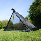 DD Hammocks Superlight Pathfinder Mesh Inner Tent set up in a grassy outdoor area with a clear blue sky.