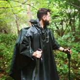 Man wearing a DD Hammocks poncho tarp for hiking in a green forest setting.