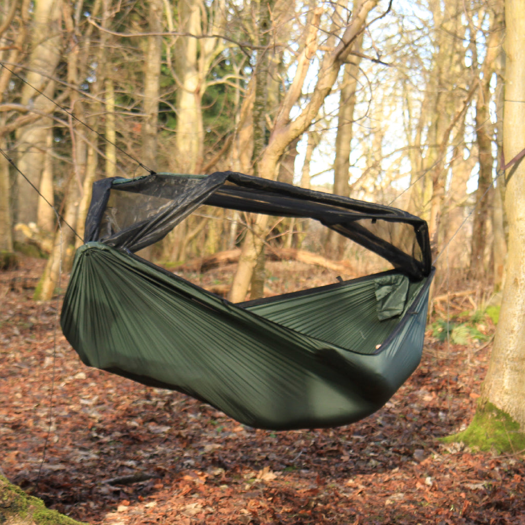 DD Superlight Frontline Hammock in a wooded setting, featuring a lightweight design and protective mesh. DD Superlight Frontline Hammock in a wooded setting, featuring a lightweight design and protective mesh.
