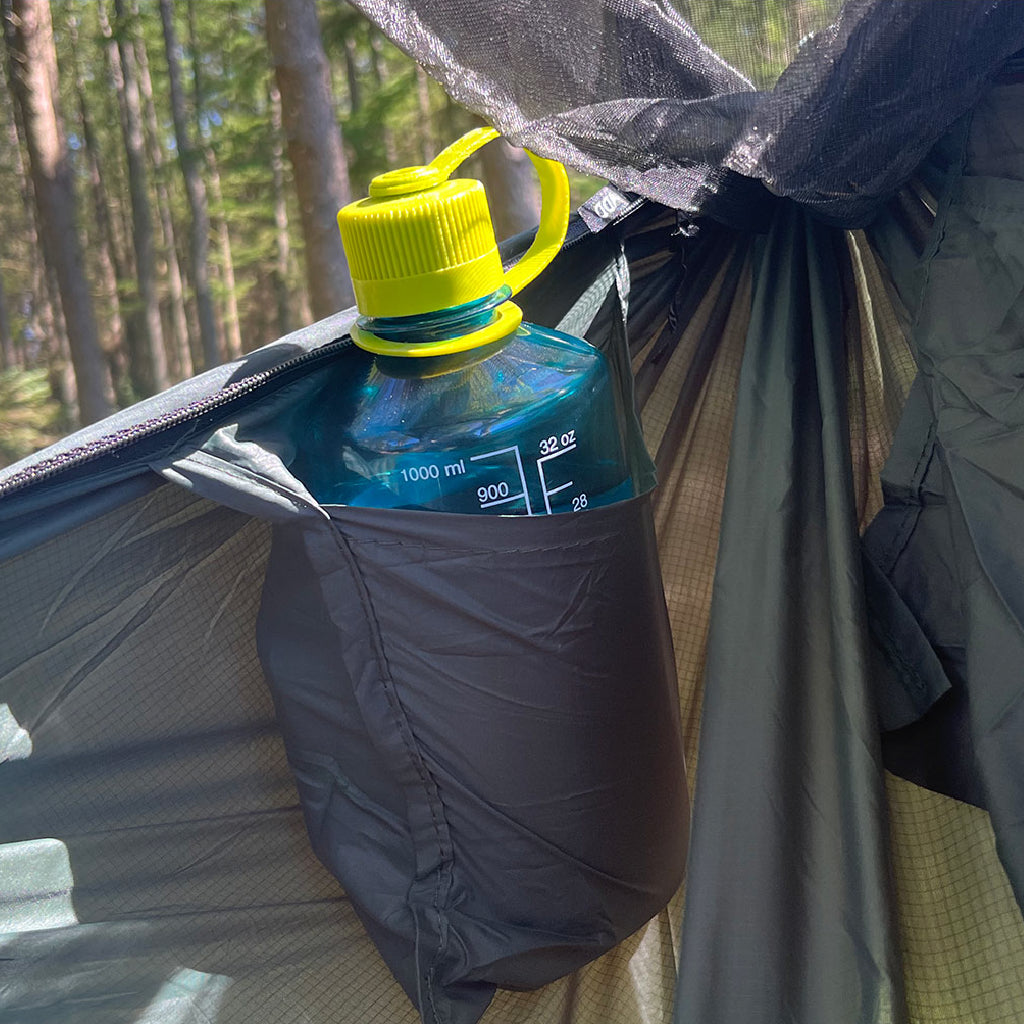 DD Superlight Frontline Hammock featuring a water bottle holder with a clear bottle and yellow lid. DD Superlight Frontline Hammock featuring a water bottle holder with a clear bottle and yellow lid.