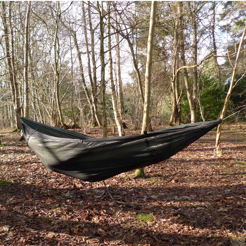 DD Superlight Frontline Hammock suspended between trees in a forest, showcasing its lightweight design. DD Superlight Frontline Hammock suspended between trees in a forest, showcasing its lightweight design.