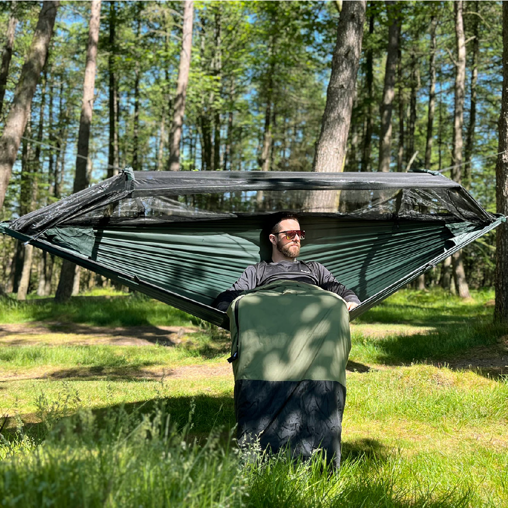 Man relaxing in a DD Superlight Frontline Hammock set up in a lush forest, showcasing its lightweight design. Man relaxing in a DD Superlight Frontline Hammock set up in a lush forest, showcasing its lightweight design.