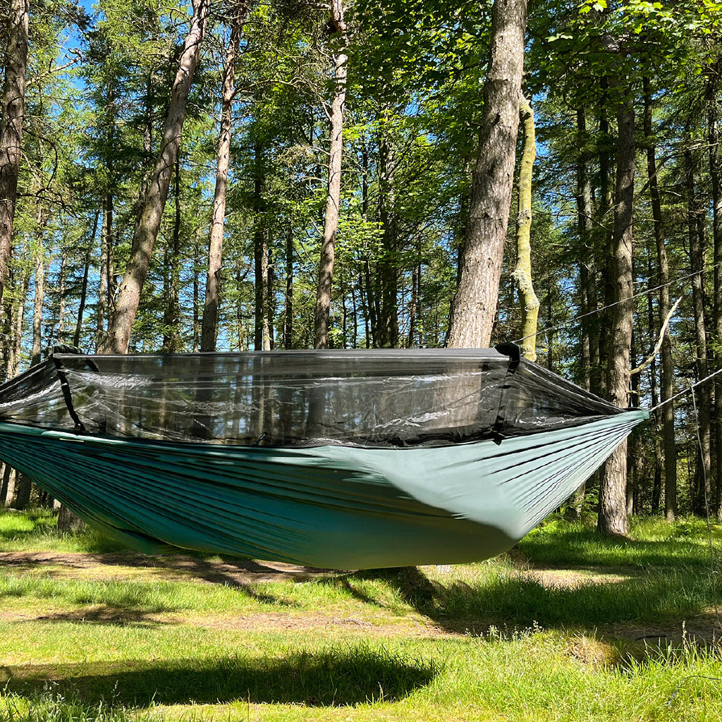 DD Superlight Frontline Hammock in a forest setting with bug net, lightweight design and suspension kit visible. DD Superlight Frontline Hammock in a forest setting with bug net, lightweight design and suspension kit visible.