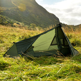 DD Superlight Tarp Tent set up in a grassy field with mountains in the background, ideal for lightweight camping.