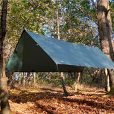 DD Tarp Medium set up over a hammock in a forest, providing shelter for camping and hiking.