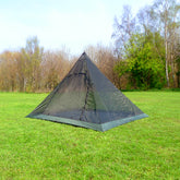 DD Superlight XL Pyramid Mesh Tent set up in a grassy field, perfect for solo travelers and lightweight camping gear.