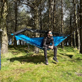 Person relaxing in a DD Hammocks jungle hammock, surrounded by trees and nature.