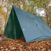 DD Superlight Tarp XL set up in a forest, providing shelter among autumn leaves, perfect for camping and outdoor activities.