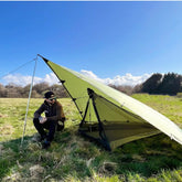 Man relaxing under the DD Tarp 3x3 - UV50+ in a grassy field, showcasing UV protection and versatility.