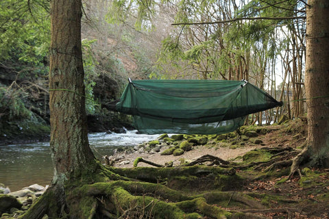 DD Hammock Mosquito Net set up between trees near a serene river, providing insect protection for camping.