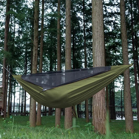 Green hammock hanging between trees in a forest setting