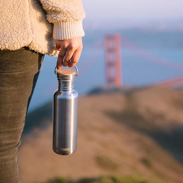 klean_kanteen_reflect_metal_water_bottle_on_bridge_with_outdoor_background
